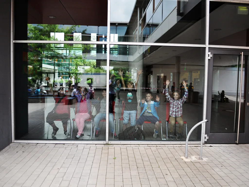 Spiegelung der Zuschauer in der Glasfassade der Schule.